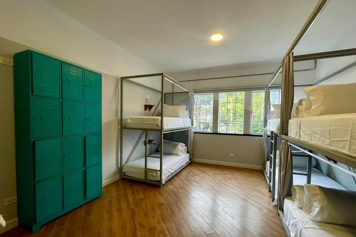 A room with bunk beds, a teal locker, and a window with a view.