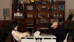 Une pièce comprenant un bureau, deux chaises, une bibliothèque et un radiateur.