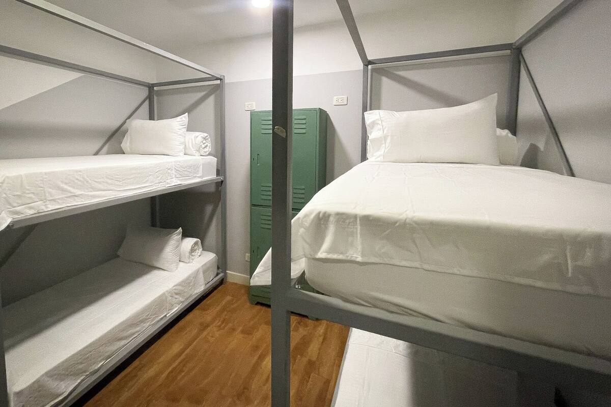 A bunk bed room with a wooden floor, green lockers, and a white wall.