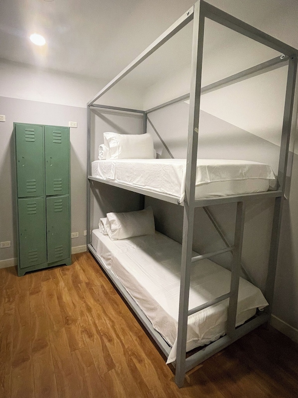 A bunk bed with white bedding, a green locker, and a wooden floor. - Marietta - House of Social Travellers (Bogotá)