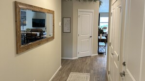 A hallway with a wooden floor, a white door, and a mirror on the left wall. - Brand New Luxury Townhouse Getaway in Lewiston, Idaho!   (Lewiston)