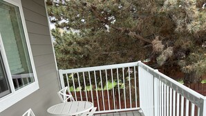 A wooden deck with a white railing, a table, and two chairs. - Brand New Luxury Townhouse Getaway in Lewiston, Idaho!   (Lewiston)