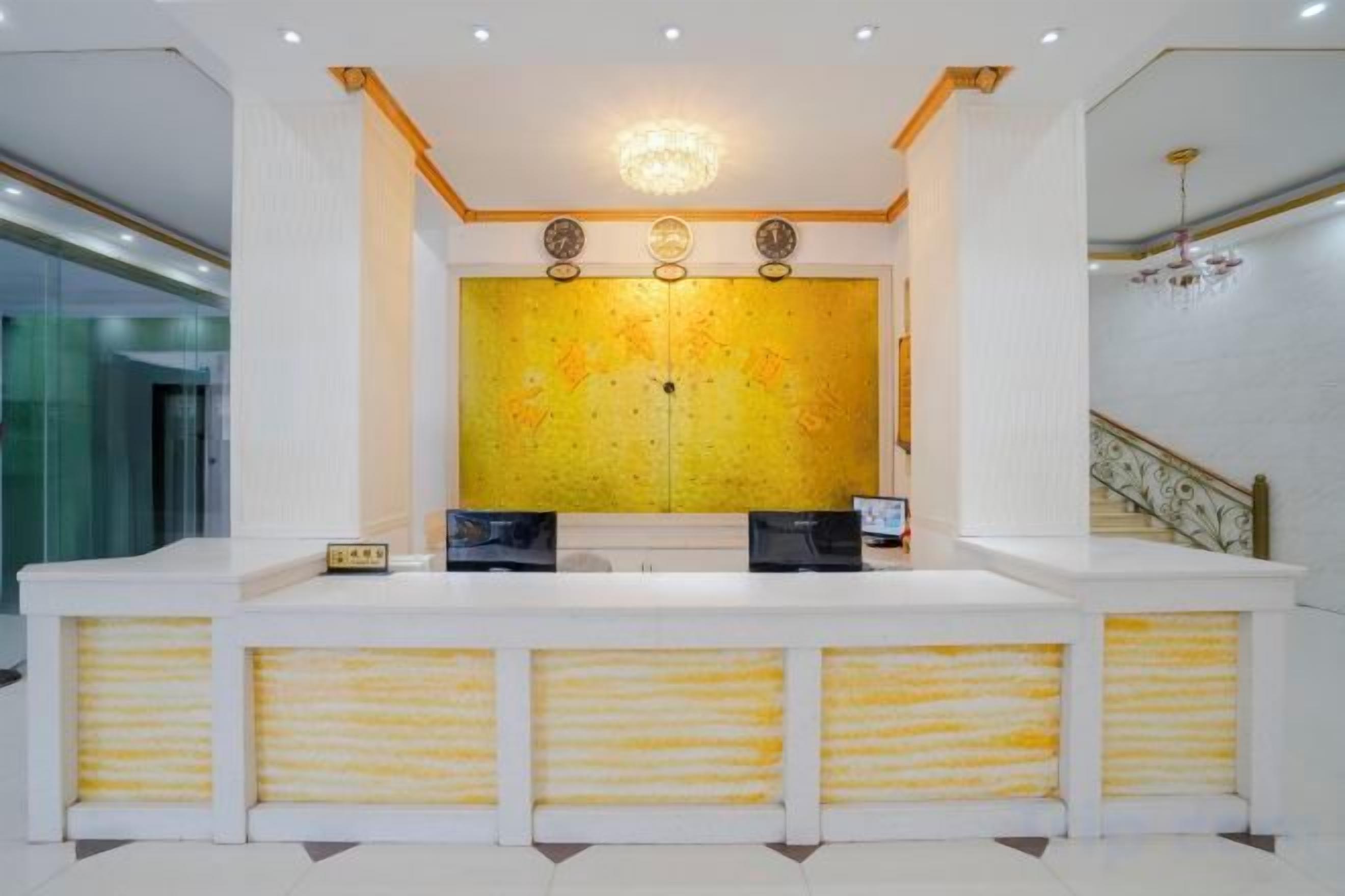 A reception area with a large yellow patterned wall, a reception desk, and a staircase.
