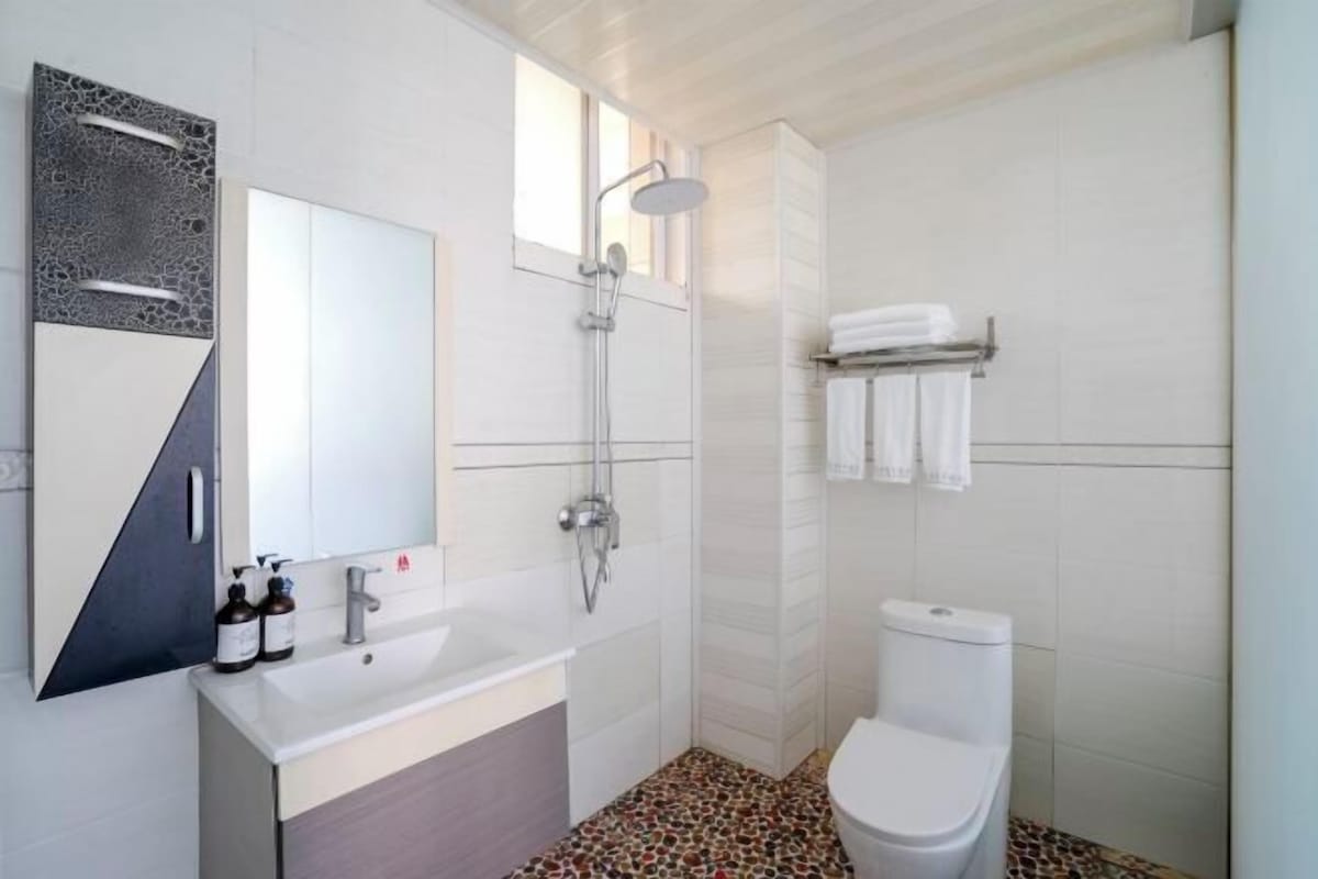A modern bathroom with a shower, toilet, and sink.