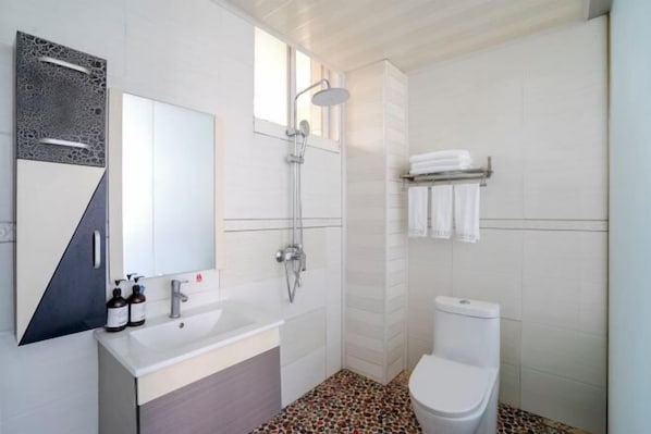 A modern bathroom with a shower, toilet, and sink.