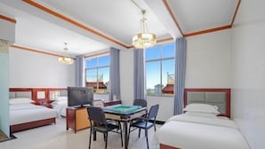 Une chambre d’hôtel avec deux lits, un bureau avec une télévision et de grandes fenêtres.