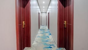 Un couloir avec des portes en bois et un tapis à motifs.