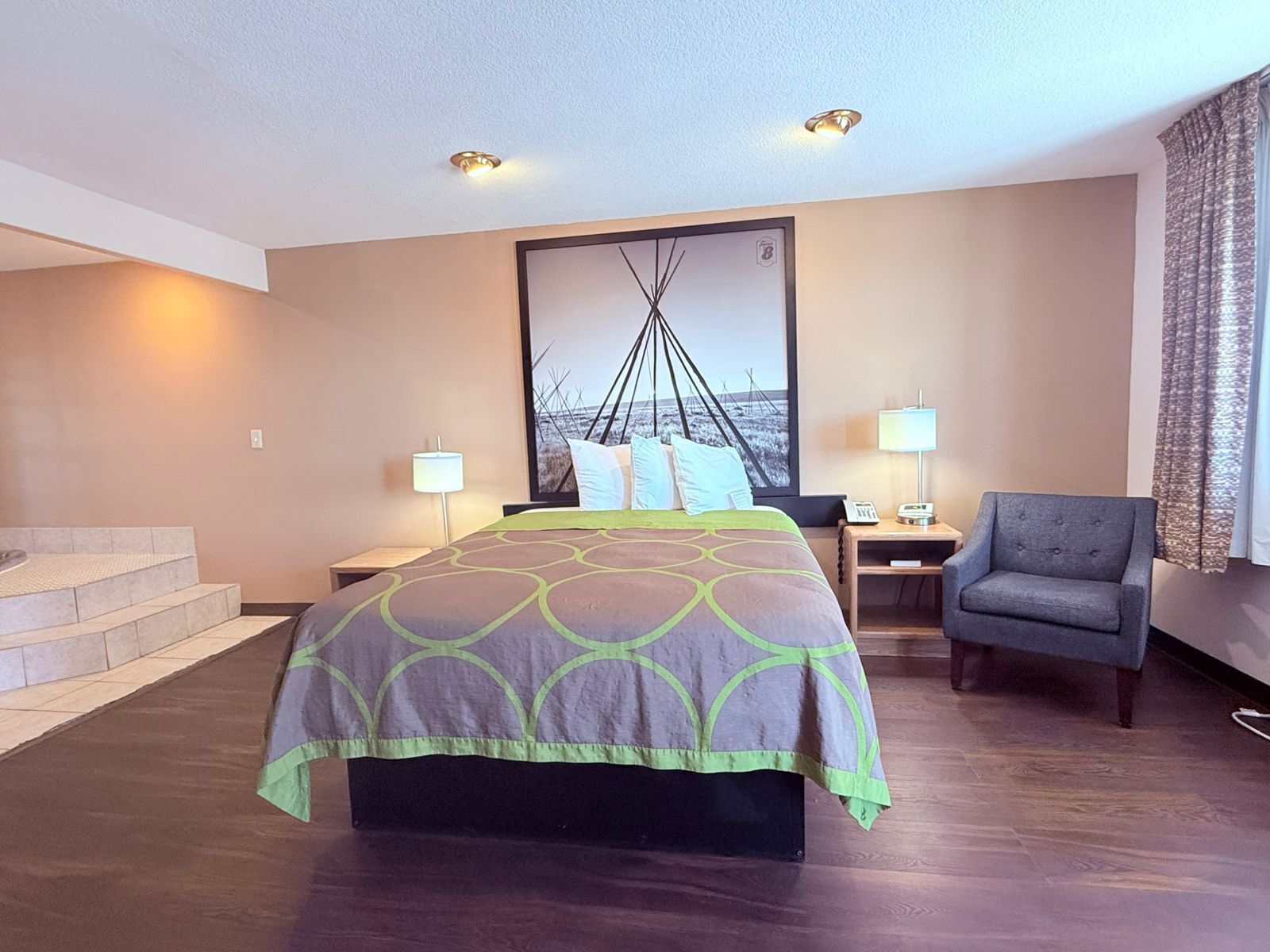 Een hotelkamer met een groot bed, twee nachtkastjes, een stoel en een trap.