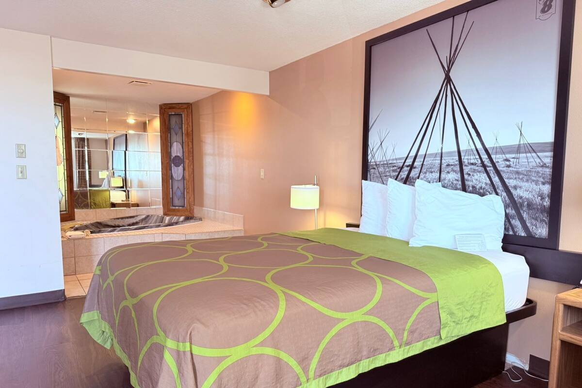 Une chambre d’hôtel avec un grand lit, une vue sur la plage, une salle de bain avec un miroir et un téléviseur fixé au mur.