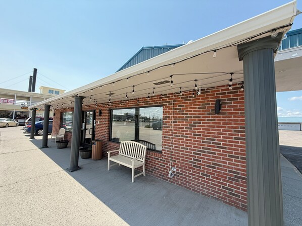 A covered outdoor seating area with brick walls and a bench.