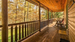 Eine Veranda mit Holzgeländer, einer Bank und einem Tisch.