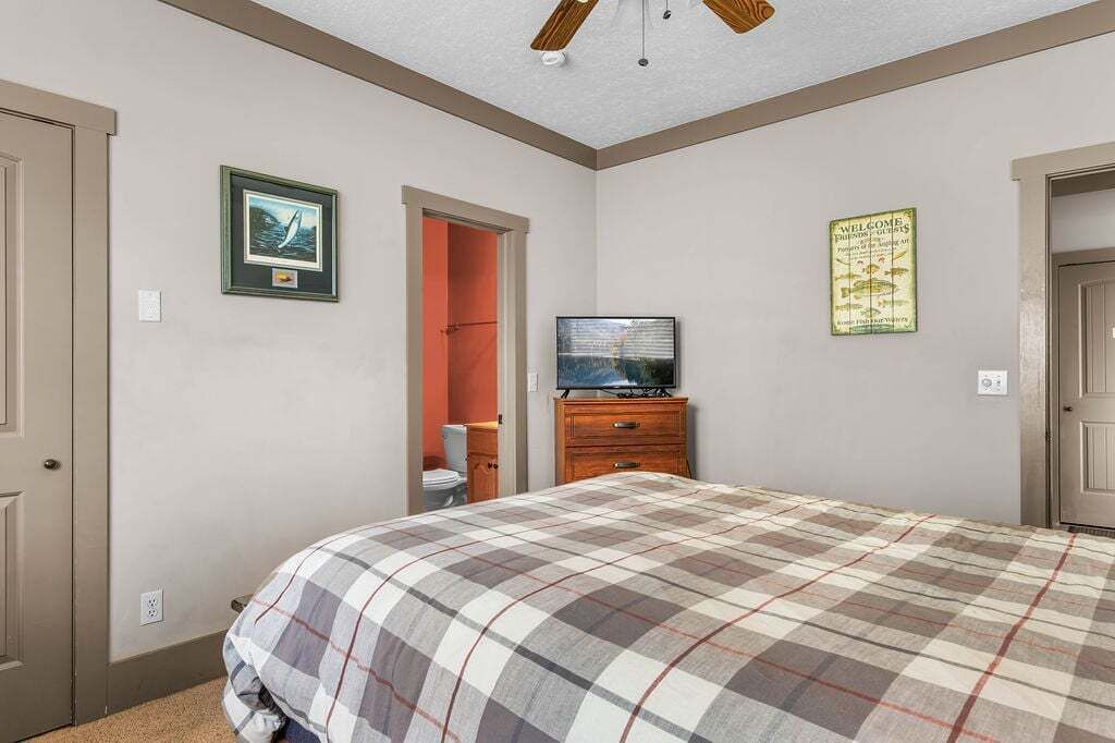 Een slaapkamer met een bed, een televisie op een dressoir en een lijst aan de muur.