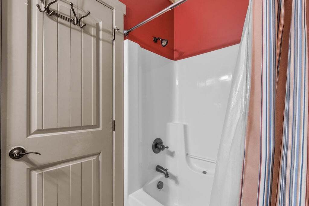A bathroom with a white door, a shower curtain, and a towel rack.