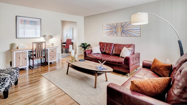 A modern living room with a leather sofa, a coffee table, a desk with a chair, and a floor lamp. - Cozy 2bd 2ba near Nob Hill home Garage Parking (Albuquerque)