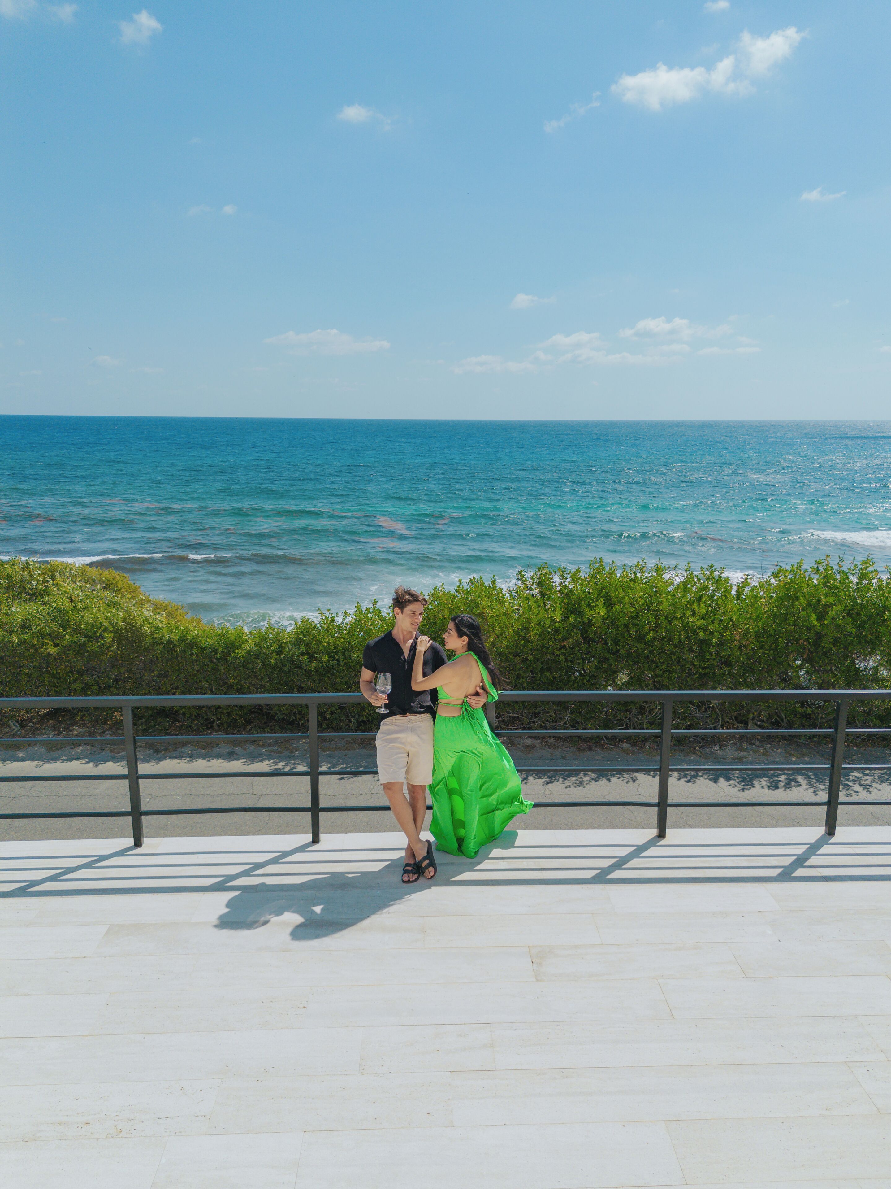A couple dancing on a promenade with a view of the ocean.