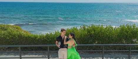 A couple dancing on a promenade with a view of the ocean.