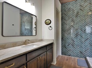 Un baño con un espejo grande, un lavamanos y una pared con diseño de espiga.