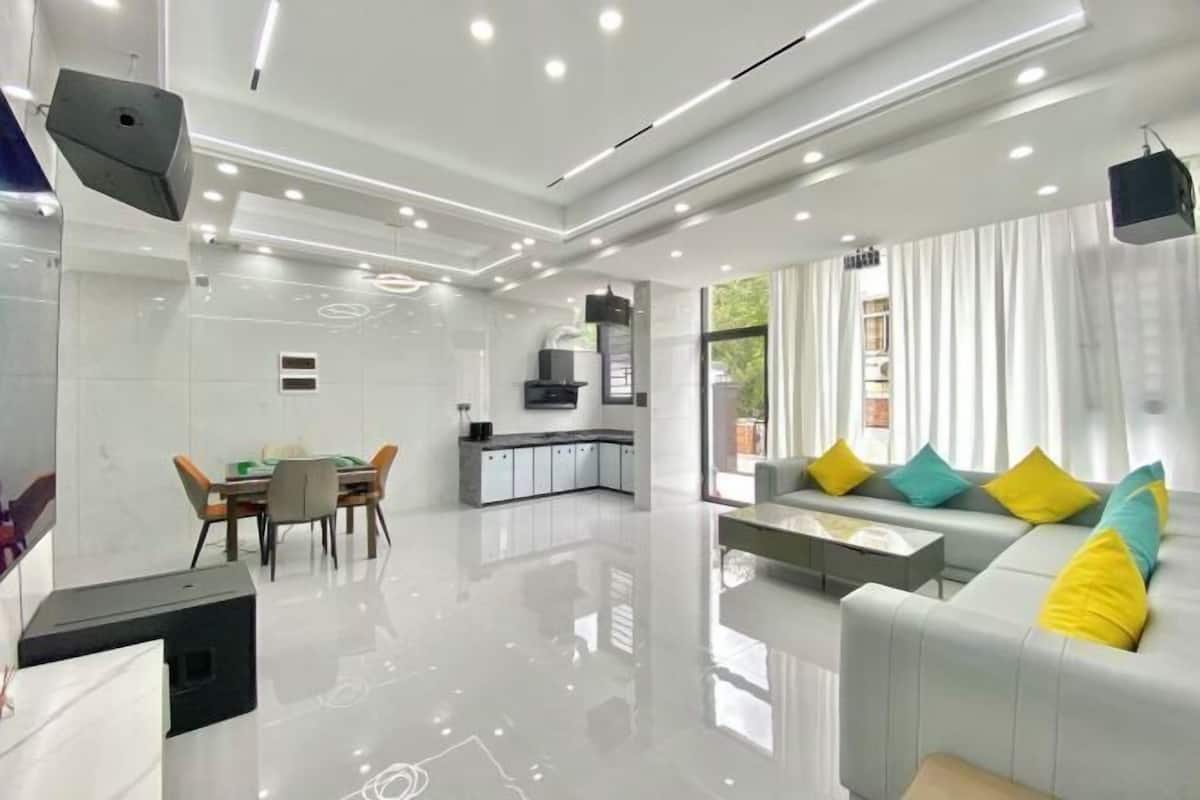 A modern living room with a sofa, a dining table, and a kitchen area.