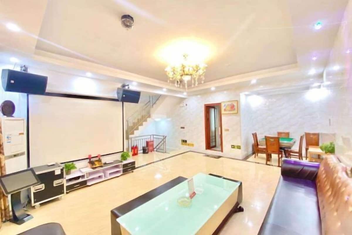 A modern living room with a glass coffee table, a sofa, a dining area with a table and chairs, and a staircase leading to another floor.
