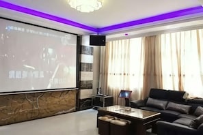 A modern living room with a large screen, a sofa, a coffee table, and a television. - Bishui Xincun Yuese Villa (Guangzhou)