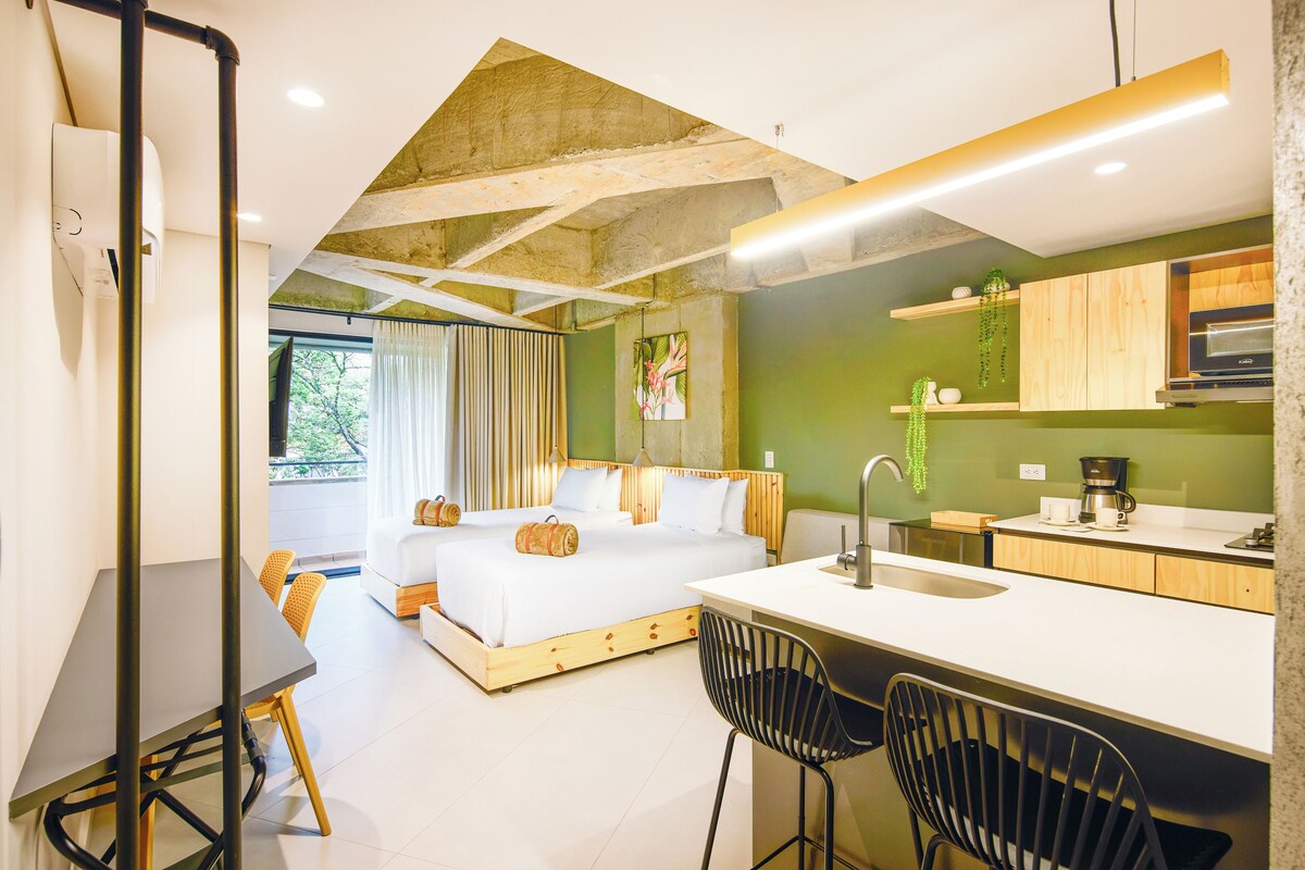 Una habitación de hotel moderna con una cama grande, una kitchenette, un comedor y vistas al exterior.