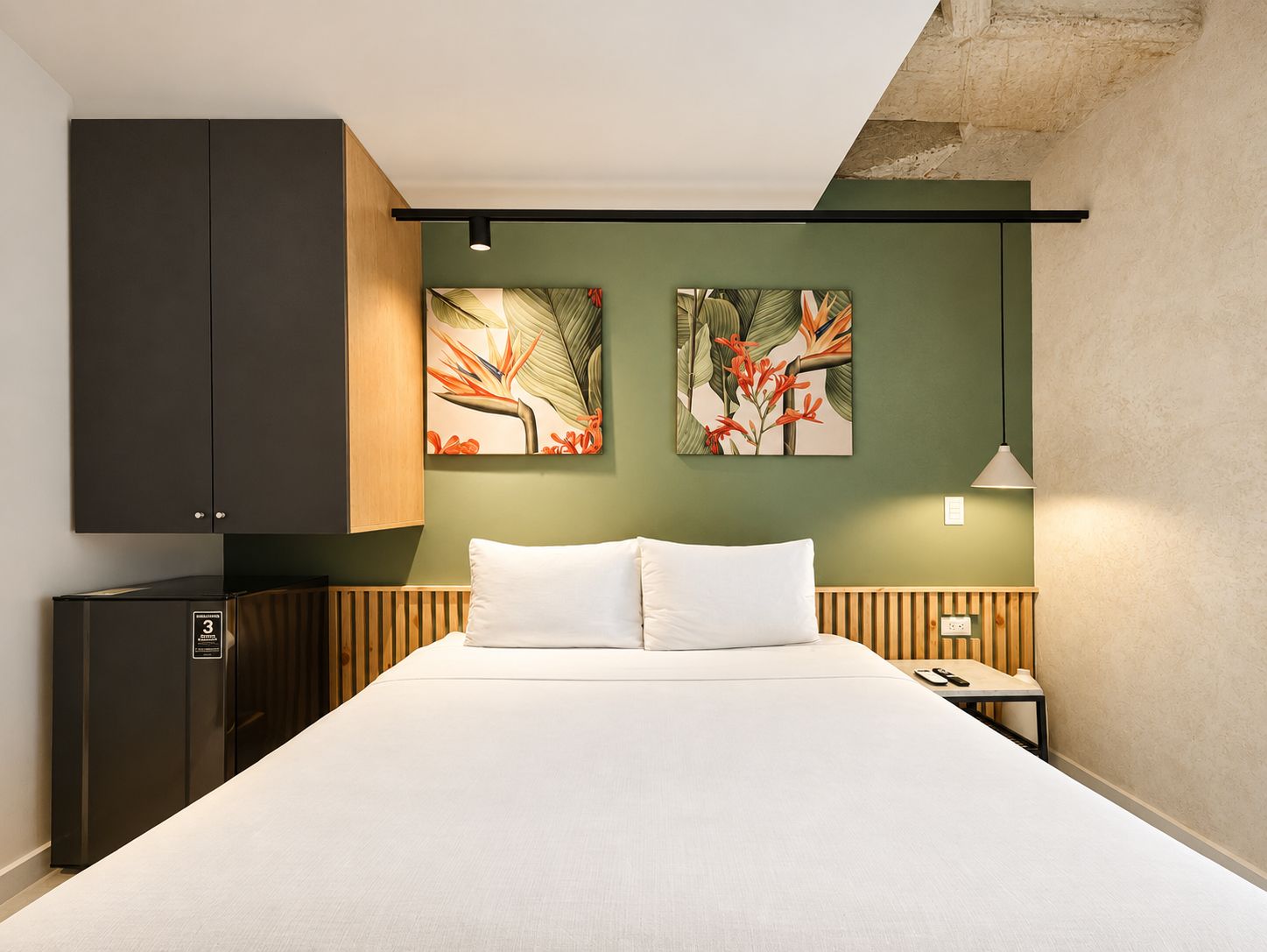 A hotel room with a bed, a nightstand, a lamp, a wardrobe, and two wall-mounted artworks.