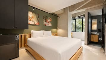A modern bedroom with a large bed, a built-in wardrobe, and artwork on the wall.