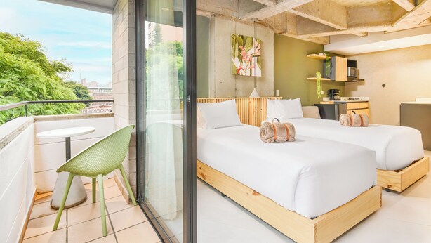 A modern bedroom with a large bed, a small table, and a chair.