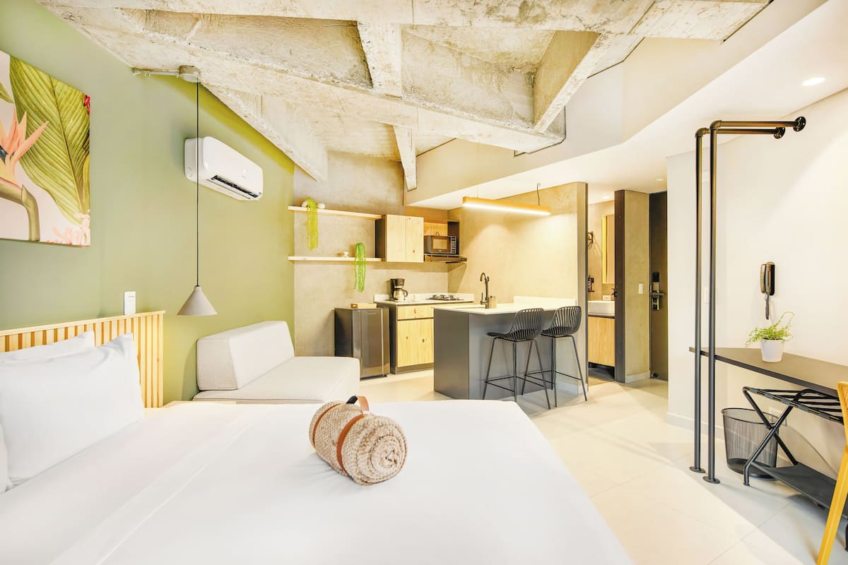 Una habitación de hotel moderna con una cama grande, una kitchenette pequeña y una zona de comedor.