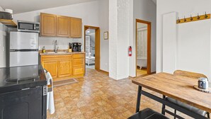 A kitchen with wooden cabinets, a microwave, a refrigerator, and a dining area with a table and chairs. - Serenity suite 1-bedroom house, AC, WiFi, minutes from Minneapolis, pet friendly (Minneapolis)