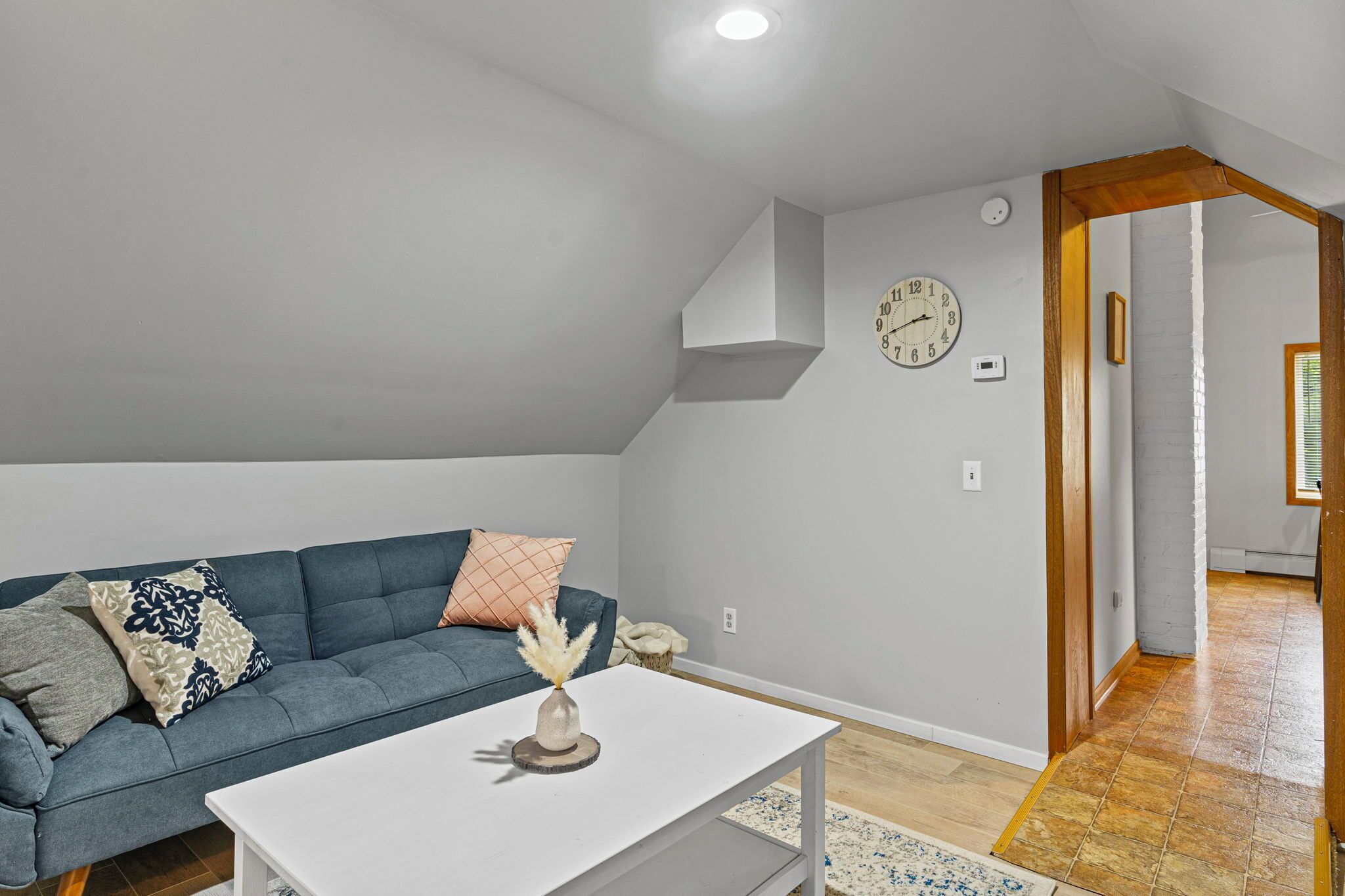 A modern living room with a blue sofa, a white coffee table, and a clock on the wall.