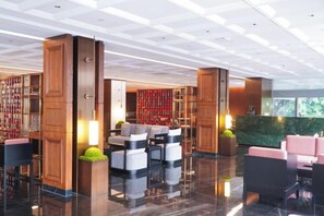 A modern lobby with a high ceiling, wooden columns, and a seating area with sofas and armchairs. - Meridian Hotel (Chongqing)