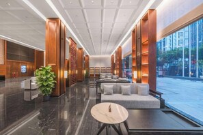 Un vestíbulo moderno con mostrador de recepción, zona de estar y amplias ventanas.