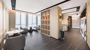 A modern hotel lobby with seating, a large bookshelf, and a laundry area. - Meridian Hotel (Chongqing)