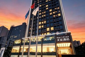Un edificio de hotel con un letrero que dice 'Meridian' y un asta con banderas.