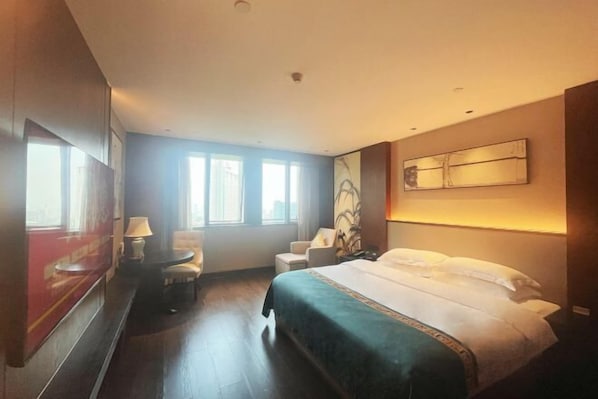 Una habitación de hotel con una cama grande, un escritorio, una silla y un ventanal.