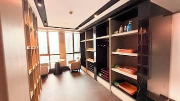 Corredor de hotel com área de estar, prateleiras com objetos e vista através de grandes janelas.