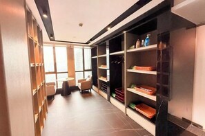 A hotel corridor with a seating area, shelves with items, and a view through large windows. - Meridian Hotel (Chongqing)