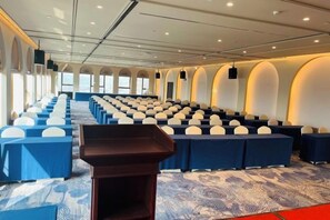 Un salón de conferencias con filas de sillas, un atril y una alfombra estampada.