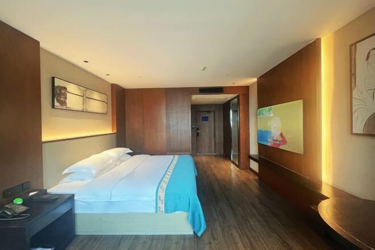 Una habitación de hotel con una cama, un escritorio con teléfono y un televisor en la pared.
