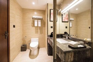 Un baño moderno con inodoro, lavamanos y un espejo grande.