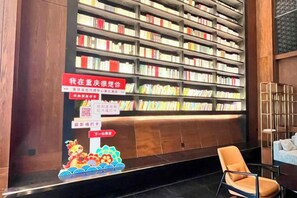 A library with bookshelves and a chair. - Meridian Hotel (Chongqing)