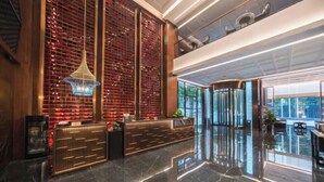 A modern lobby with a reception desk, a large red patterned wall, and a glass partition. - Meridian Hotel (Chongqing)