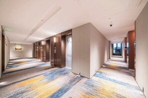 A hotel corridor with a patterned carpet, elevator doors, and a reception area. - Meridian Hotel (Chongqing)