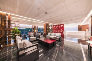 Un salón amplio con techos altos, muebles modernos y vistas a la ciudad.