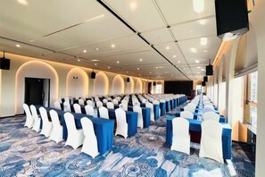 A conference room with rows of tables and chairs, equipped with microphones and screens. - Meridian Hotel (Chongqing)
