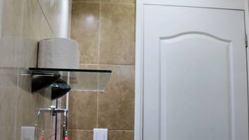 A bathroom with a glass shelf holding a towel, a sink, and a mirror.