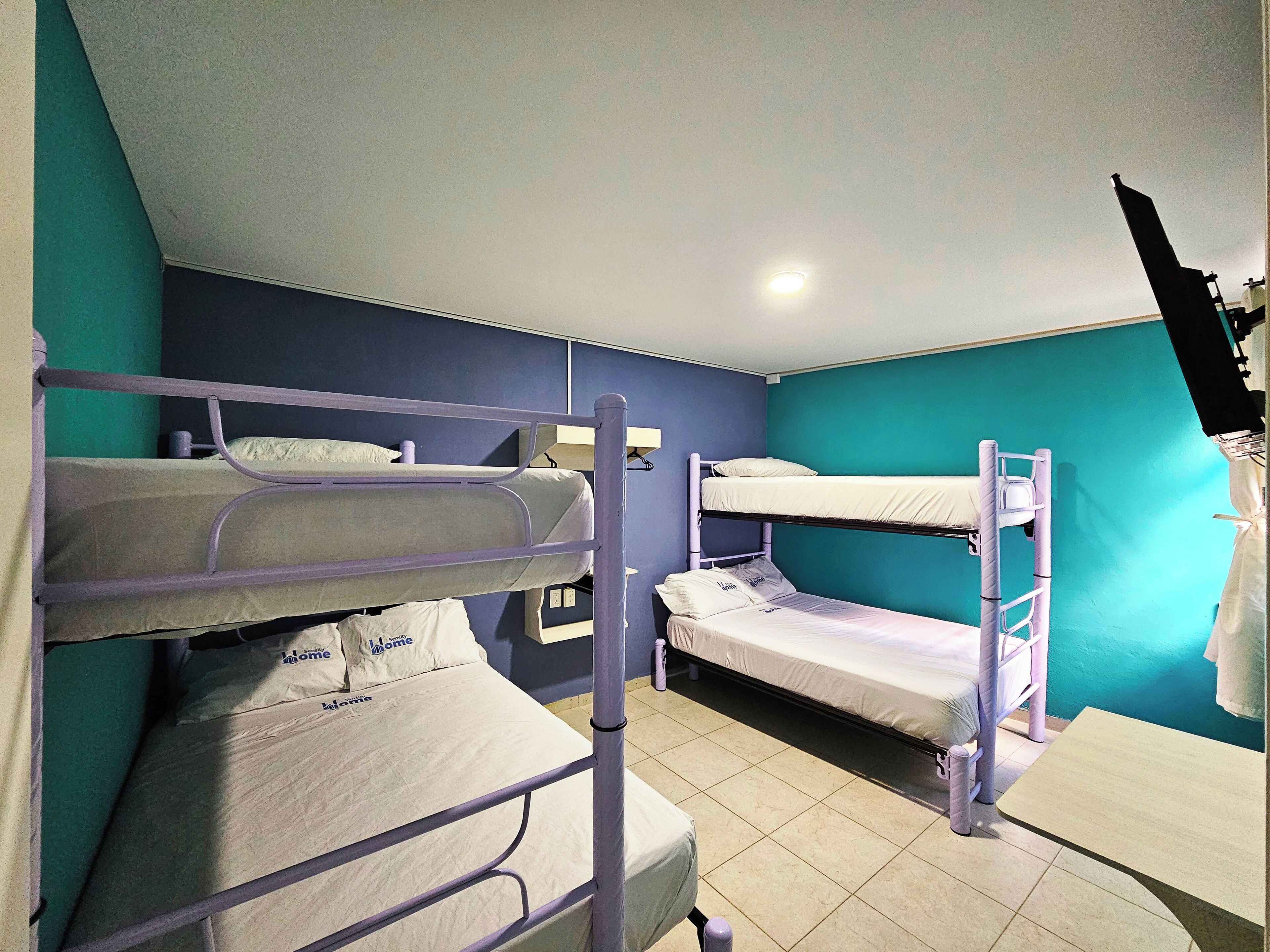 Un dormitorio con literas, una mesita pequeña y una estantería en la pared.