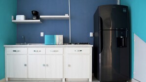 Una cocina moderna con armarios blancos, un refrigerador negro, una cafetera y una pared de acento color turquesa.