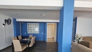 Un comedor con mesa y sillas, una ventana con cortinas y una puerta que da a otra habitación.